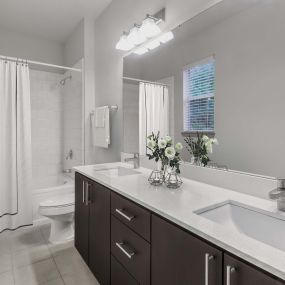Bathroom with double sinks, cabinet storage, a window with natural light, and a shower/bathtub at Camden Asbury Village in Raleigh, NC.