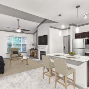 Open concept kitchen and living room at Camden Asbury Village in Raleigh, NC.  The kitchen features stainless steel appliances and a center island.  The living room features an electric fireplace, ceiling fan, tall ceilings, and a doorway to an exterior private balcony.