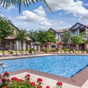 Expansive pool with palm trees, flowers, and lounge chairs at Camden Asbury Village in Raleigh, NC.