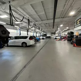 Jeff Wyler Chrysler Dodge Jeep Ram of Fort Thomas Service Department showcased in this photo, featuring vehicles lifted off the ground with tires stacked around, highlighting expert auto repair, maintenance, and efficient service operations in a large, well-equipped garage.