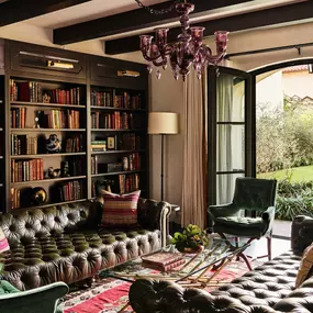 Library-style suite with bookshelves, green armchair, and window view to greenery.