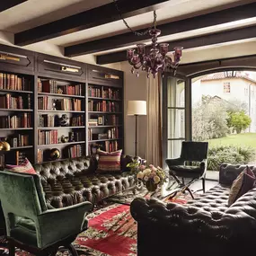 Reading room with tufted sofa, bookshelves, and a window view.