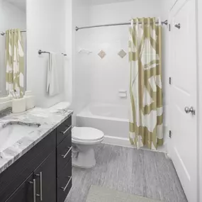 Bathroom with granite countertops and bathtub with curved shower rod at Camden Dulles Station apartments in Herndon, VA