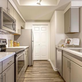 One bedroom kitchen with wood style flooring stainless steel appliances and quartz countertops