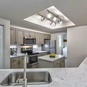 Kitchen with stainless steel appliances and greige cabinets island quartz countertops