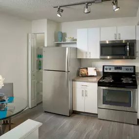 Eat in kitchen with stainless steel appliances track lighting wood look flooring and pantry