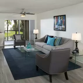 Living room and work from home area with sliding glass doors to balcony, wood-look flooring, and ceiling fan