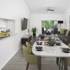 Living and dining room with sliding glass doors to patio, wood-look flooring, and ceiling fan at Camden Portofino apartments in Pembroke Pines, FL