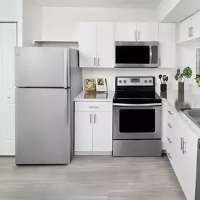 Eat in kitchen with stainless steel appliances track lighting wood look flooring and pantry at Camden Portofino apartments in Pembroke Pines, FL