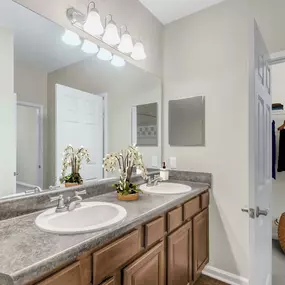 Bathroom with double sink vanity and bathtub with tile surround and curved shower rod