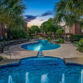 Resort style pool with fountains at dusk