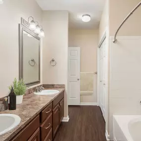 Bathroom with wood style flooring double sinks and curved shower rod