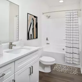 Contemporary style bathroom with quartz countertops, white shaker under mount sink, and garden bathtub at Camden Overlook Apartments in Raleigh, NC.