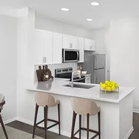 Contemporary kitchen with white quartz countertops, white shaker style cabinetry, and recessed lighting at Camden Overlook Apartments in Raleigh, NC.