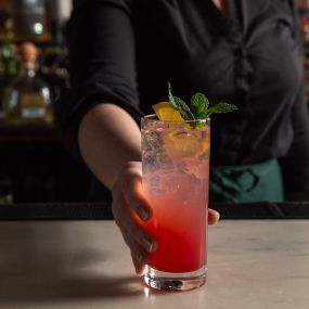 Bartender serving a fresh First Page cocktail at The Long Room in Times Square surrounded by Broadway shows