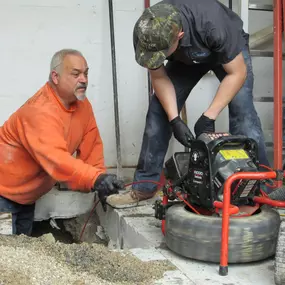 Techs on jobsite running a camera through a sewer line.