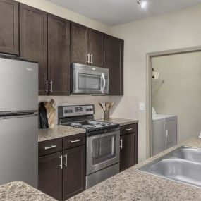 Kitchen with stainless steel appliances next to laundry room with full size washer and dryer