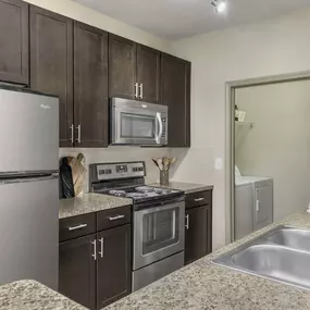 Kitchen with stainless steel appliances next to laundry room with full size washer and dryer