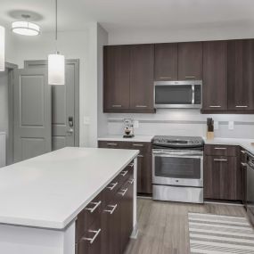 Ktichen with white quartz countertops, sleek gray cabinetry, and island