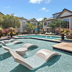 Resort-style pool with tanning ledge and in-water lounge chairs at Camden Cedar Hills apartments in Austin, TX