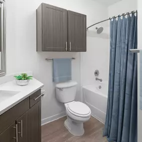 Bathroom with quartz countertops, brown cabinets and a soaking bathtub with extended shower rod