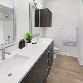 Bathroom with two sinks, white quartz countertops and brown cabinets.