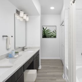 Modern finishes bathroom with double vanity, dark brown cabinetry, gray quartz countertops and white subway tile surround