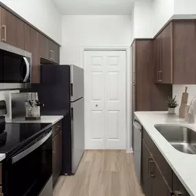 Kitchen with stainless steel appliances and gray quartz countertops at Camden Vanderbilt Apartments in Houston, Texas