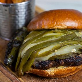 Green Chile Cheeseburger with roasted anaheim chile, white cheddar cheese, charred serrano aïoli, toasted brioche bun, tajin wedge fries