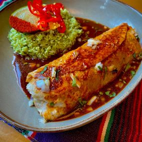 Birria Burrito with low & slow-braised beef, charro beans, dry jack cheese, pico cabbage, green rice, onion & cilantro, beef consommé