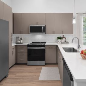 Modern finish kitchen in floor plan 9 with white quartz countertops, subway tile backsplash, and greige cabinetry.
