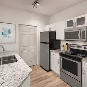 Kitchen with quartz countertops, white cabinets, and stainless steel appliances