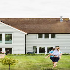 Large home with siding installation and man standing in front yard