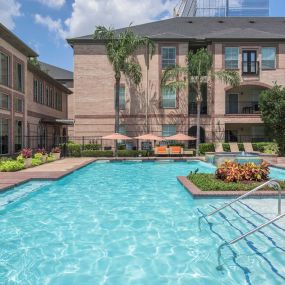 Resort-style swimming pool with umbrellas and handrails at Camden Greenway Apartments in Houston, TX