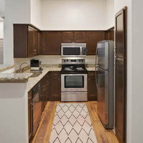 Kitchen with granite countertops, stainless steel appliances and bar seating at Camden Greenway Apartments in Houston, TX