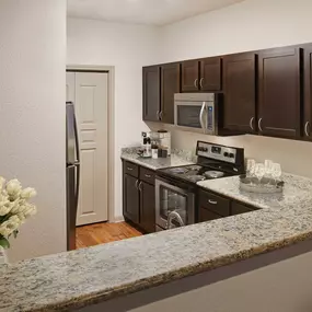 Kitchen with bar top seating and stainless steel appliances at Camden Greenway Apartments in Houston, TX