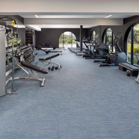 Camden Hillcrest Apartments San Diego CA fitness center with free weights dumbbells Cybex machine, treadmills and ellipticals surrounded by arched windows