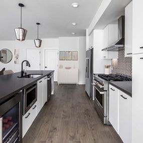 Camden Hillcrest apartments san diego ca premier kitchen with designer lighting, stainless steel appliances including a six burner stove, and dark quartz countertops