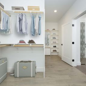 Spacious ensuite walk-in closet with wood shelves and light oak hardwood flooring