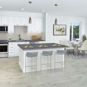 Open concept kitchen with stainless steel appliances, space for bar stool seating, dining area, and patio