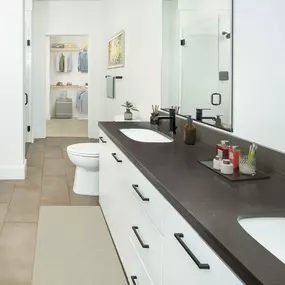 Concrete-inspired dual sink vanity in a five-fixture main bathroom with ensuite walk-in closet