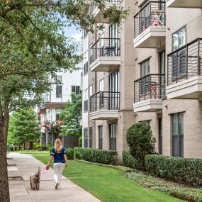 Dog-friendly community, resident walking dog on a leash next to the building