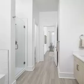 Townhome primary bathroom with wood-style flooring, white quartz countertops, soaking bathtub, and glass-door shower at Camden Belmont apartments in Dallas, TX
