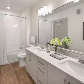 Contemporary style bathroom with curved shower rod and double vanity sinks and white quartz countertops