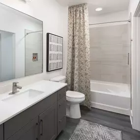 Desert modern style bathroom with gray vein quartz countertops and curved shower rod in bathtub