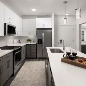 Modern style kitchen island with stainless steel appliances and gray vein quartz countertops