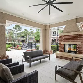 Outdoor lounge with fireplace near the pool area at Camden Grand Harbor Apartments in Katy, Tx