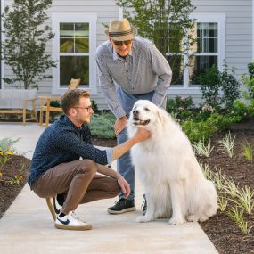 A resident and his grandson outside of the senior living community with their dog