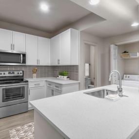 Modern style kitchen alongside laundry room with full size washer and dryer
