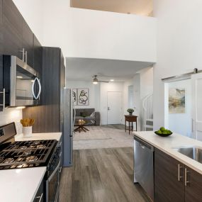 Camden Main and Jamboree Apartments Irvine CA luxury kitchen with stainless steel appliances, chrome pull-down sprayer faucet, gas stovetop, white quartz countertops, wood-like flooring throughout kitchen